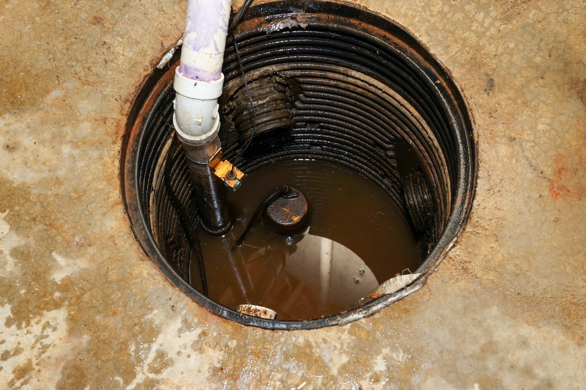 A plumber repairing a sump pump in a flooded basement in a residential home